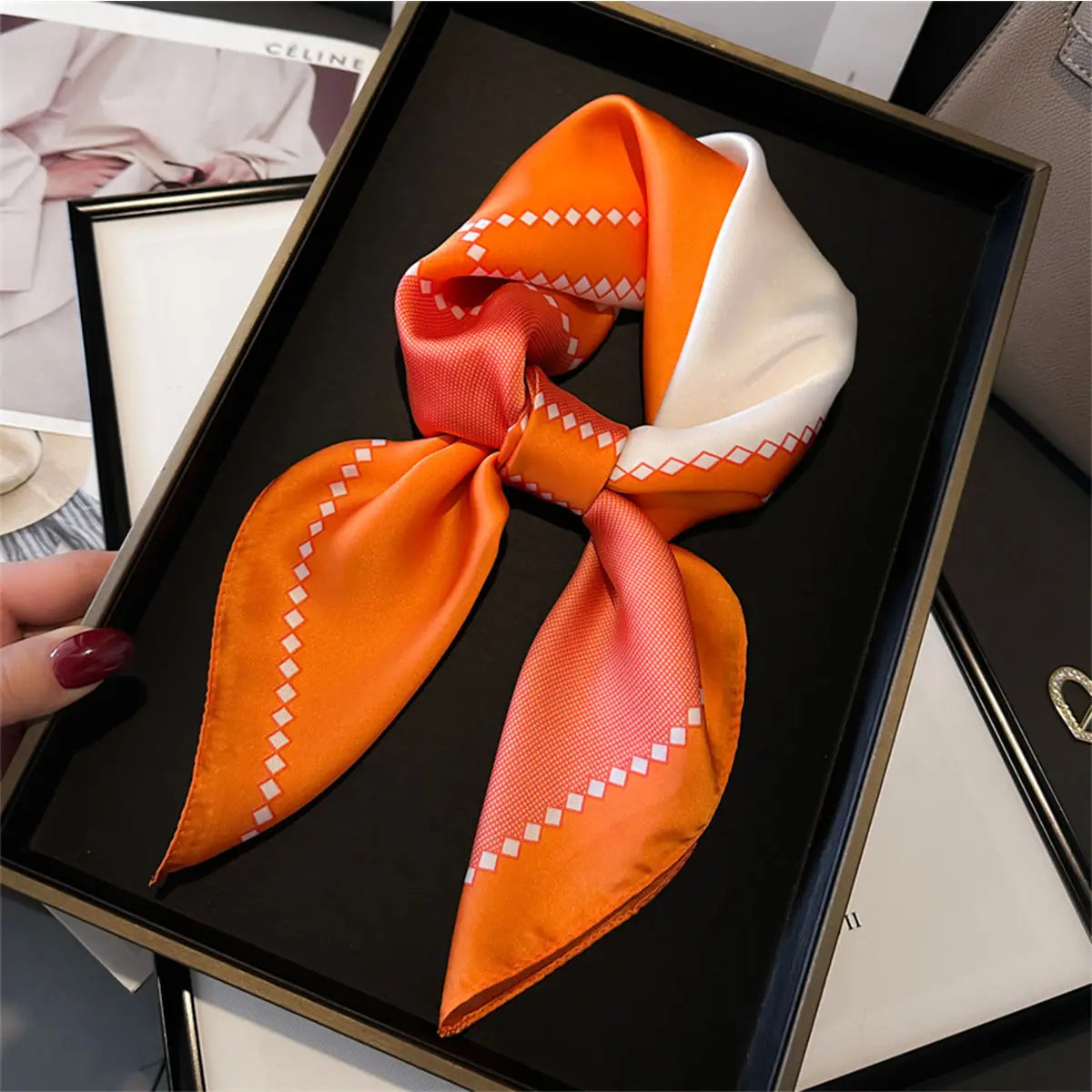 Orange and white patterned scarf on a black tray with blurred background