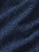 A close-up of dark blue denim fabric with a visible twill weave and soft folds.