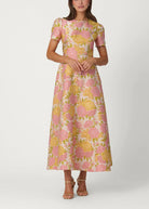 Woman wearing a floral dress with pink and yellow flowers on a white background
