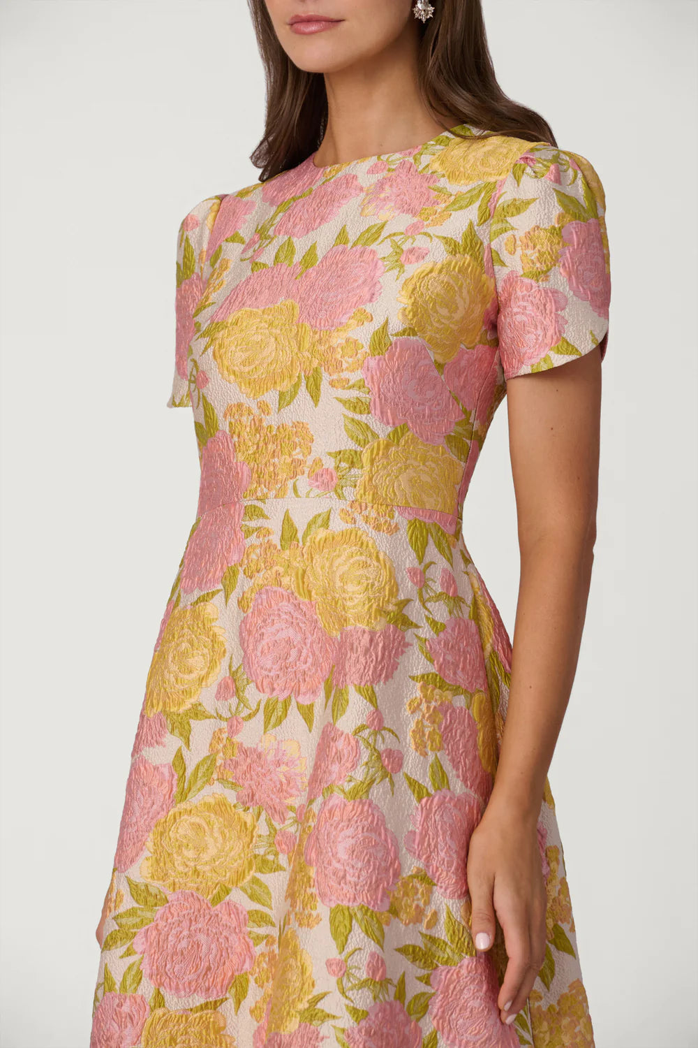 Woman wearing a floral dress with pink and yellow flowers on a white background