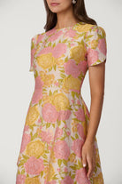 Woman wearing a floral dress with pink and yellow flowers on a white background