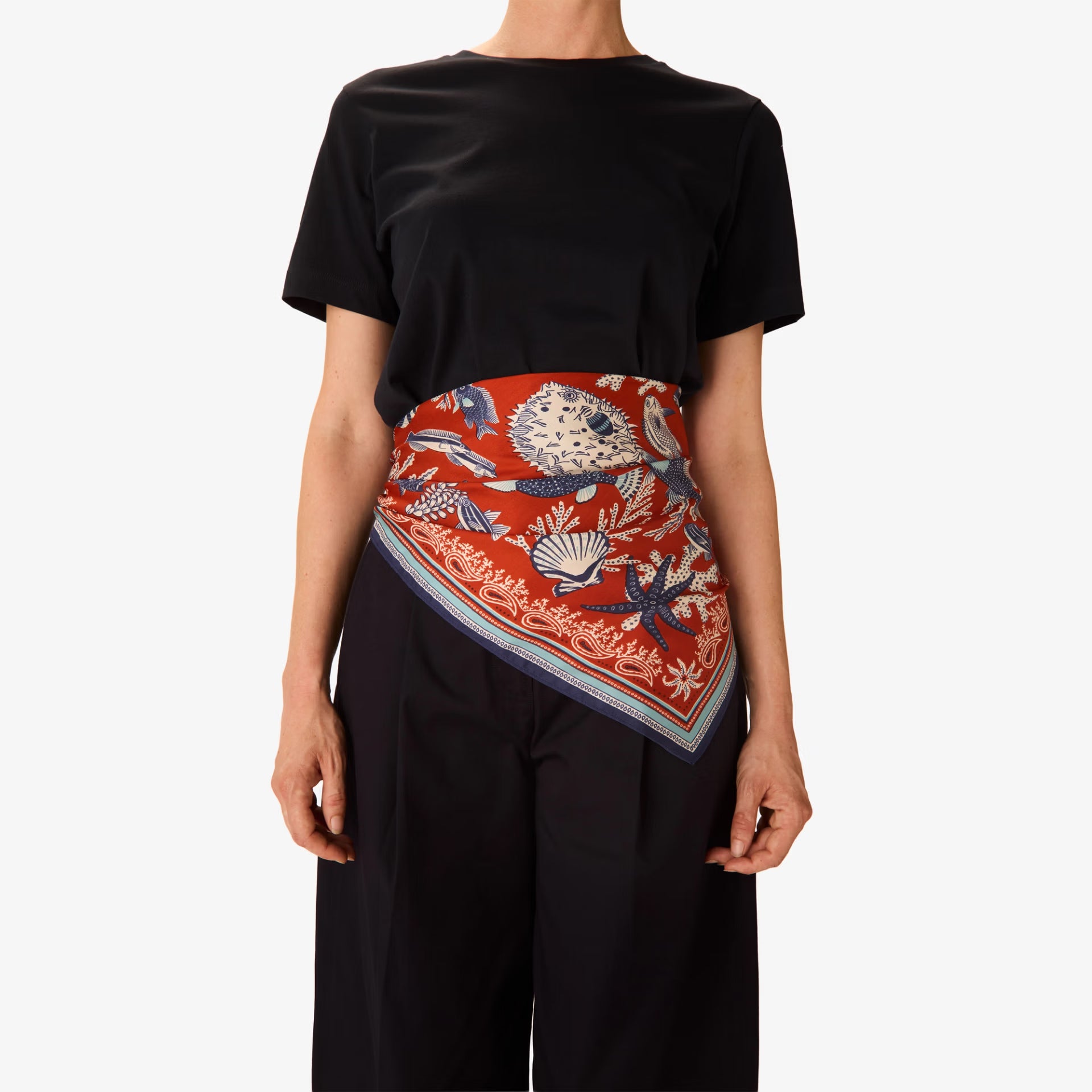 Person wearing a black t-shirt with a colorful patterned scarf draped over the shoulder on a white background