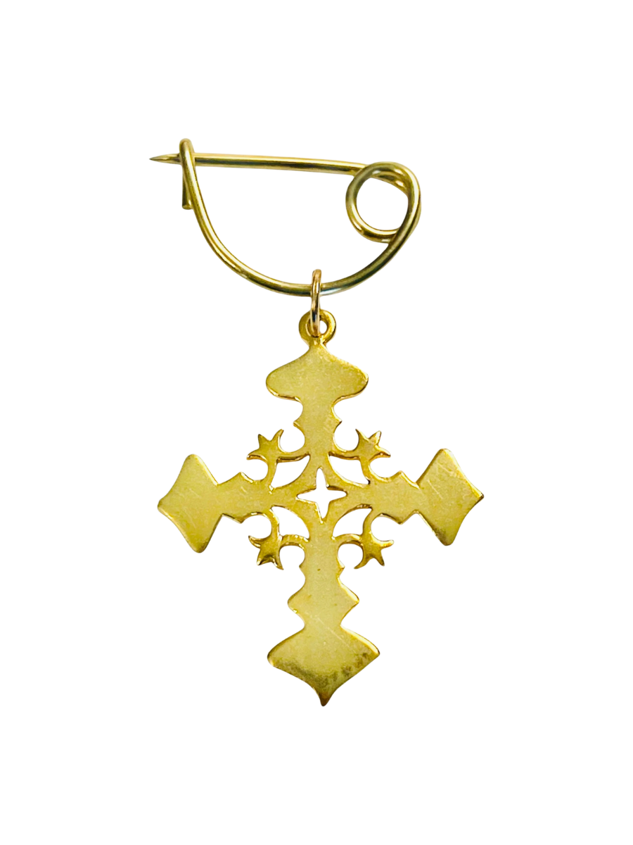 Gold cross-shaped brooch on a white background