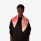 Person wearing a black outfit with a red and white patterned scarf on a white background