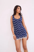Woman wearing a blue dress with white wave pattern on a white background