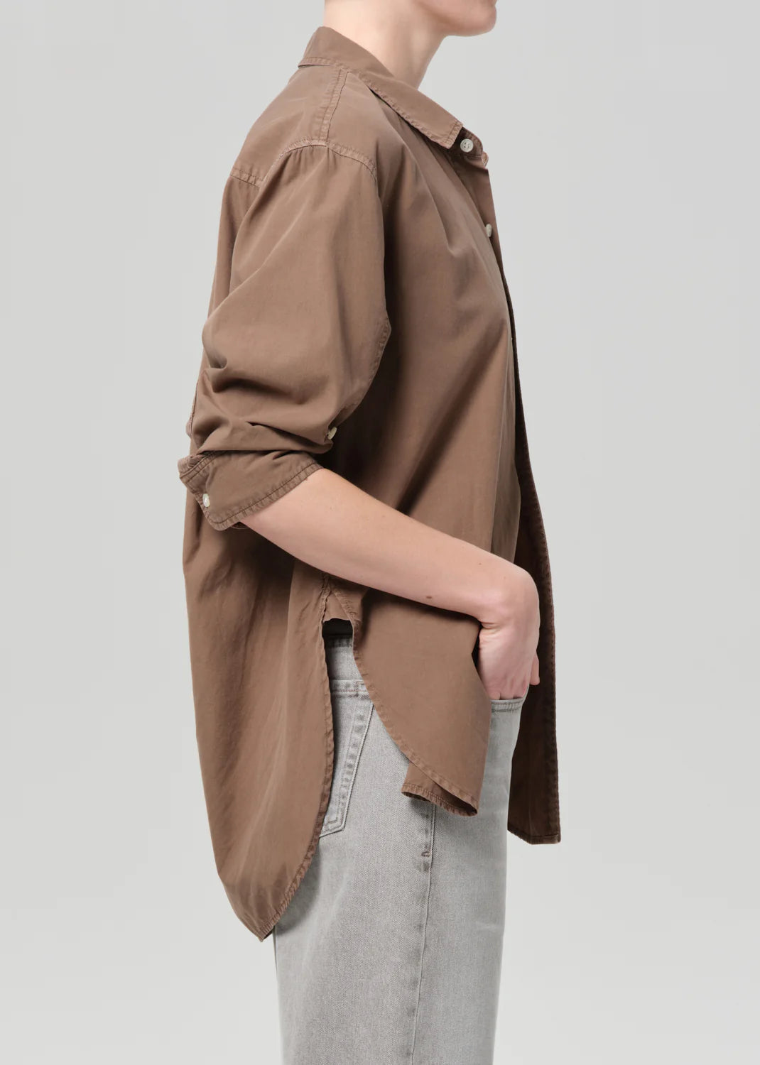 Person wearing a brown shirt and light gray pants on a plain background