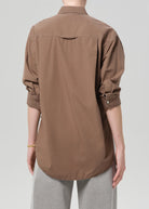 Brown button-up shirt worn by a person on a plain background