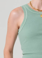Person wearing a light green ribbed tank top on a plain background