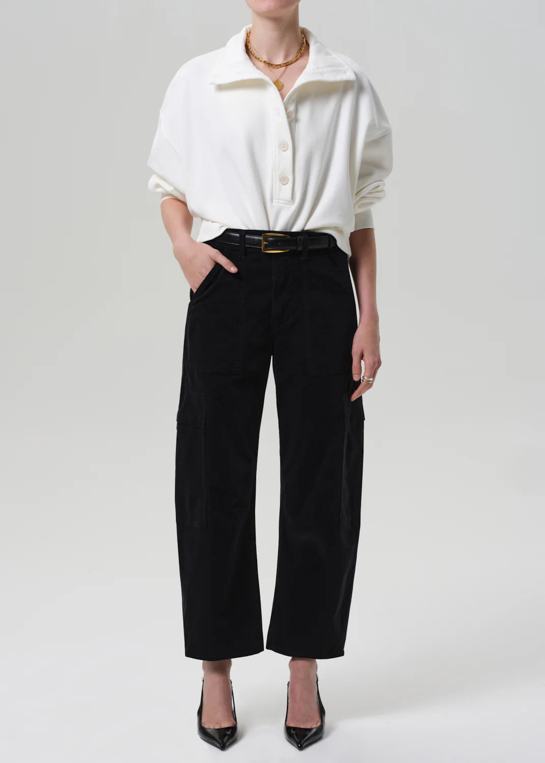 Person wearing a white shirt and black pants on a plain background