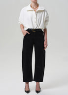 Person wearing a white shirt and black pants on a plain background