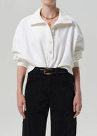 Person wearing a white shirt and black pants on a plain background