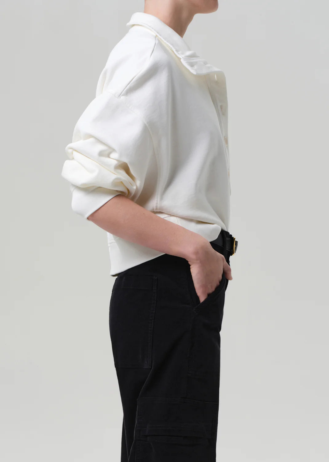Person wearing a white shirt and black pants on a plain background