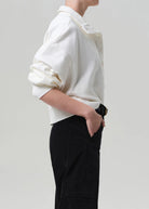 Person wearing a white shirt and black pants on a plain background
