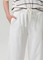 White pants with a drawstring waist on a plain background