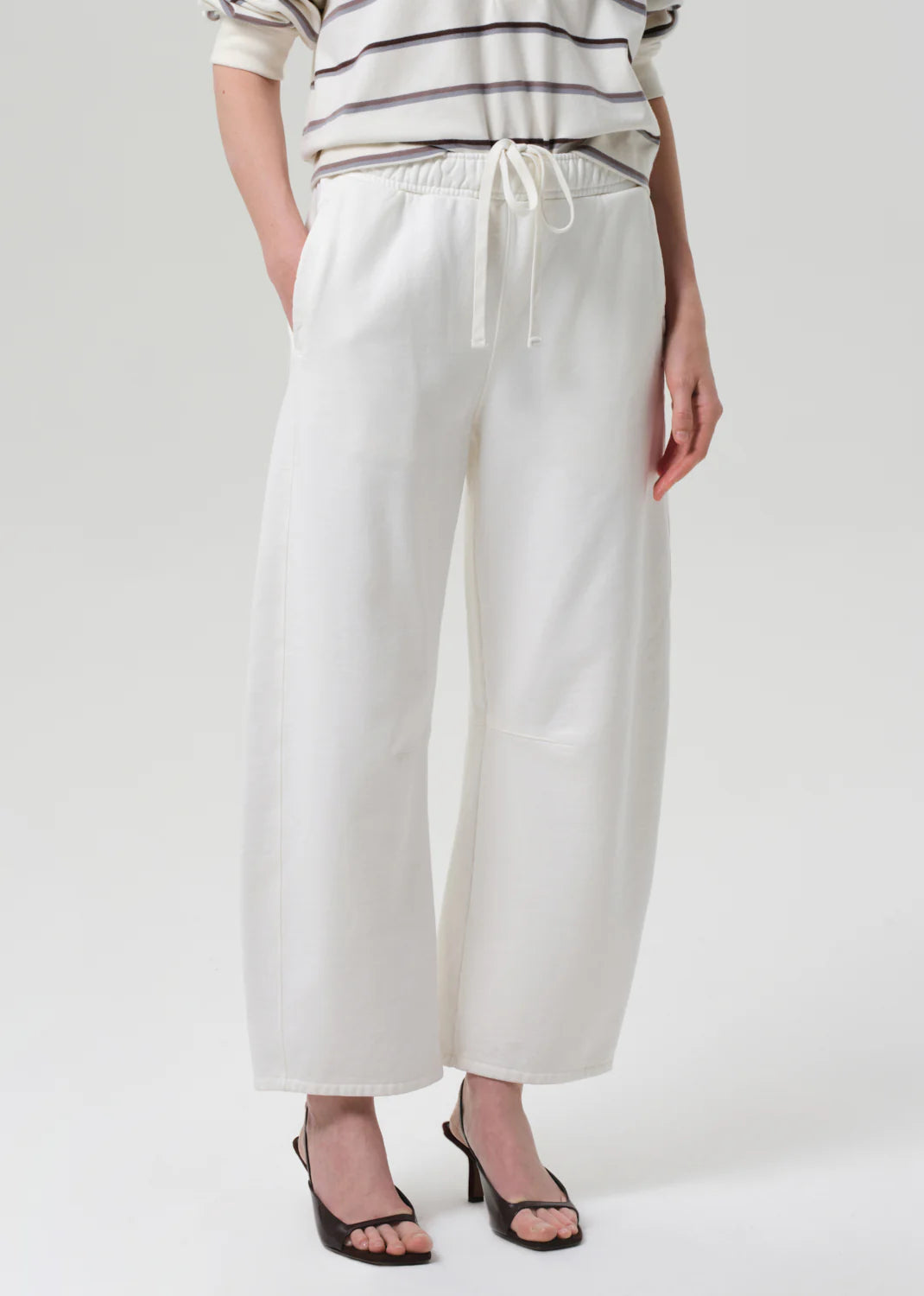 Person wearing white wide-leg pants and a striped shirt on a plain background