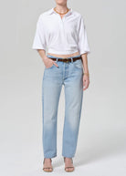 Person wearing a white shirt and light blue jeans on a plain background