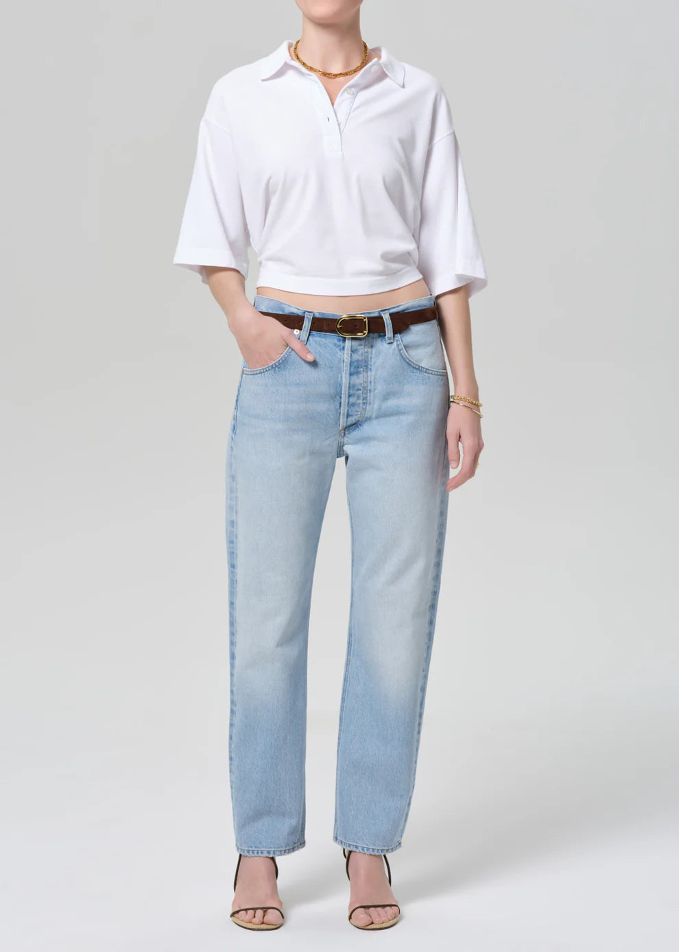 Person wearing a white shirt and light blue jeans on a plain background