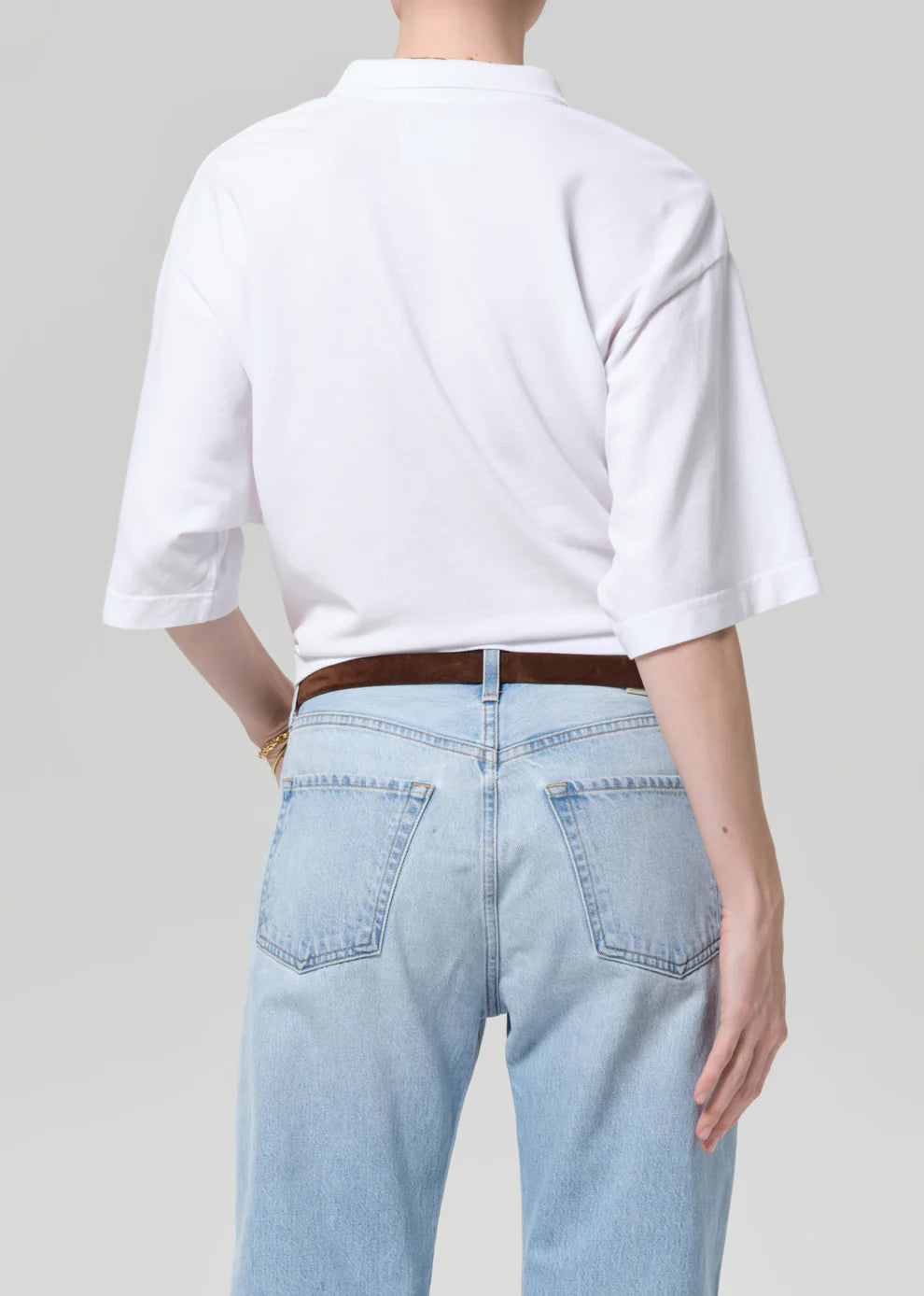 Person wearing a white t-shirt and light blue jeans on a plain background