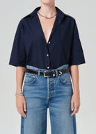 Person wearing a navy blue shirt and blue jeans on a plain background