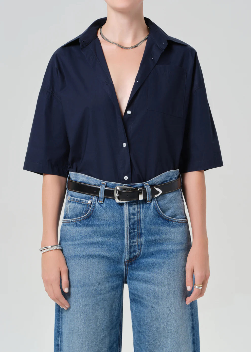 Person wearing a navy blue shirt and blue jeans on a plain background
