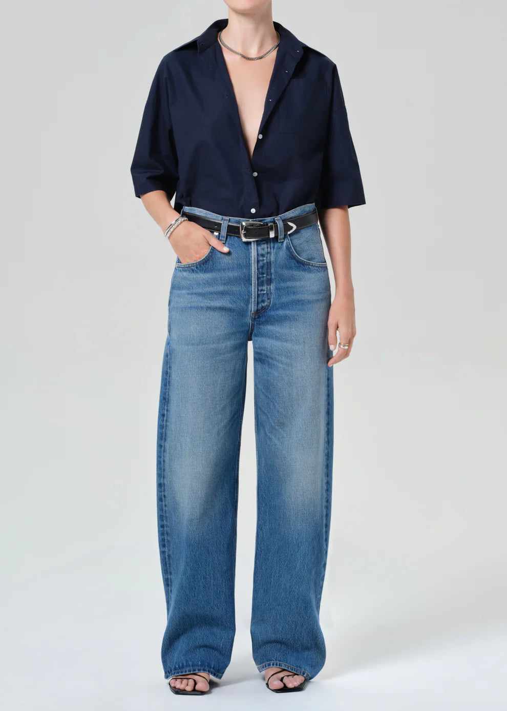 Person wearing a navy shirt and blue jeans on a white background