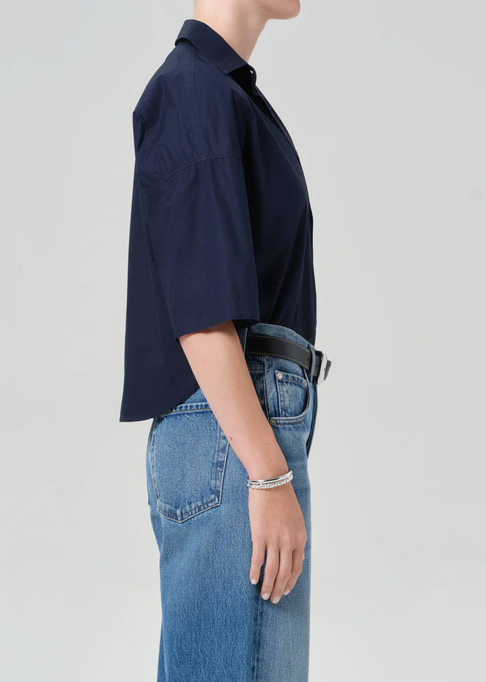 Person wearing a navy shirt and blue jeans on a light gray background