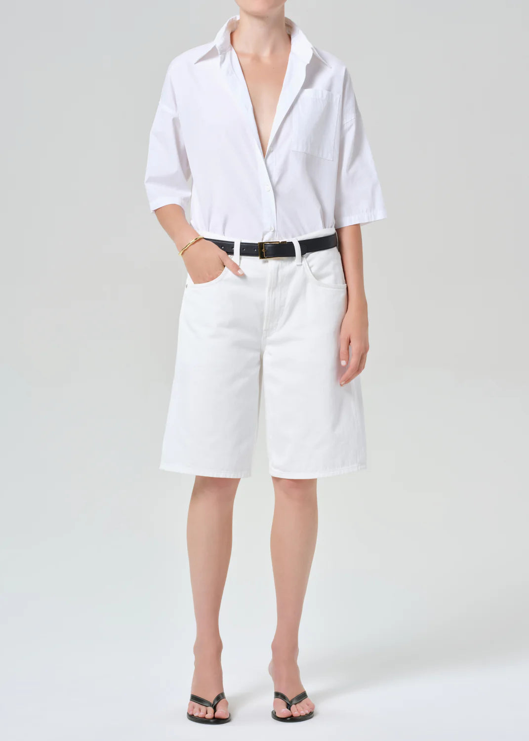 Person wearing a white shirt and white shorts on a plain background
