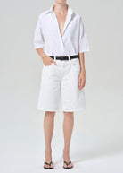 Person wearing a white shirt and white shorts on a plain background