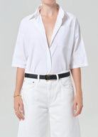 Person wearing a white button-up shirt and white pants on a plain background