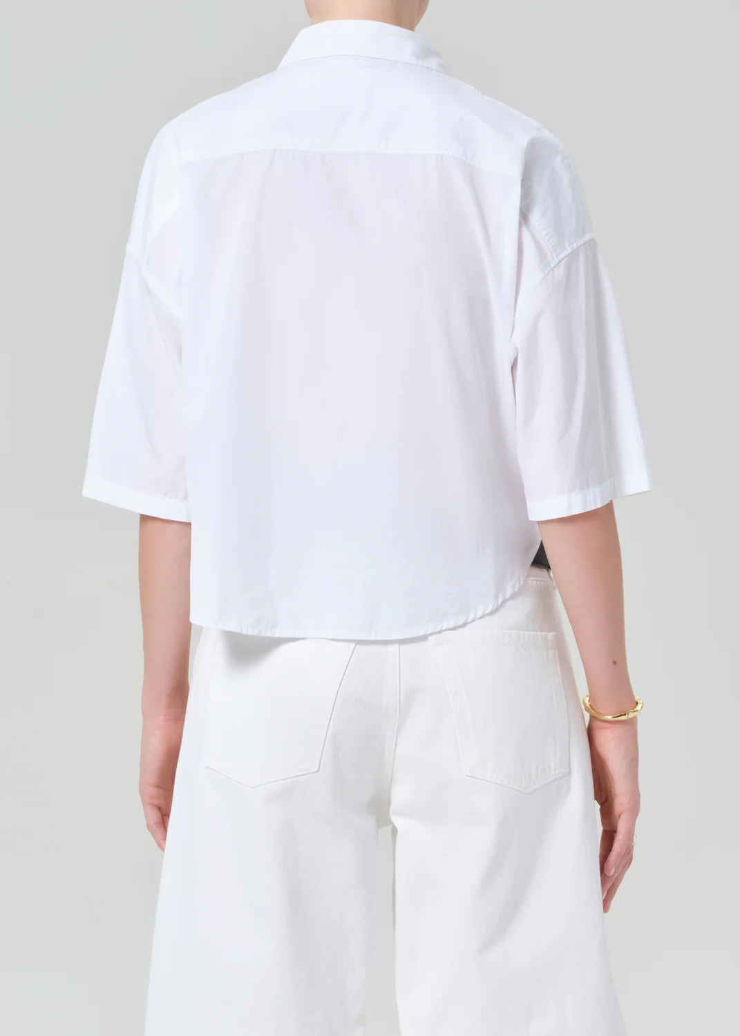Person wearing a white shirt and pants on a plain background