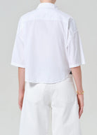Person wearing a white shirt and pants on a plain background