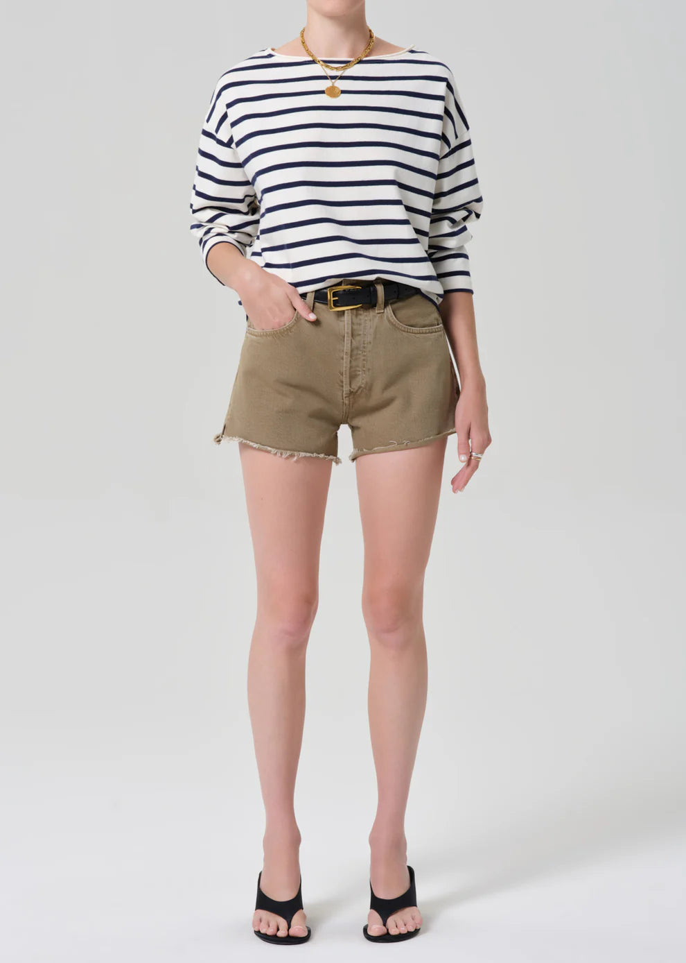 Person wearing a striped shirt and beige shorts on a white background