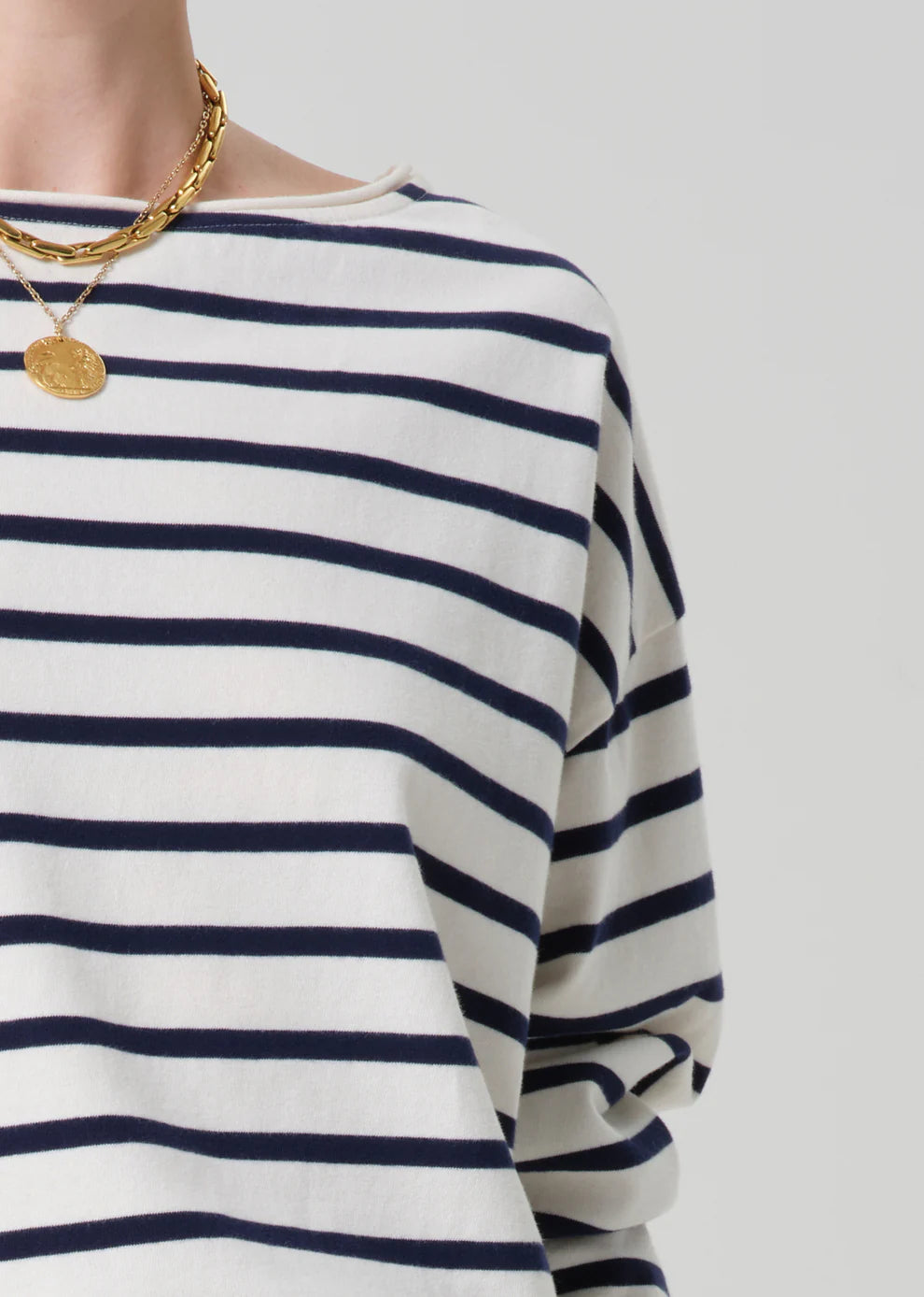 Navy and white striped long-sleeve shirt with gold necklace on a light gray background