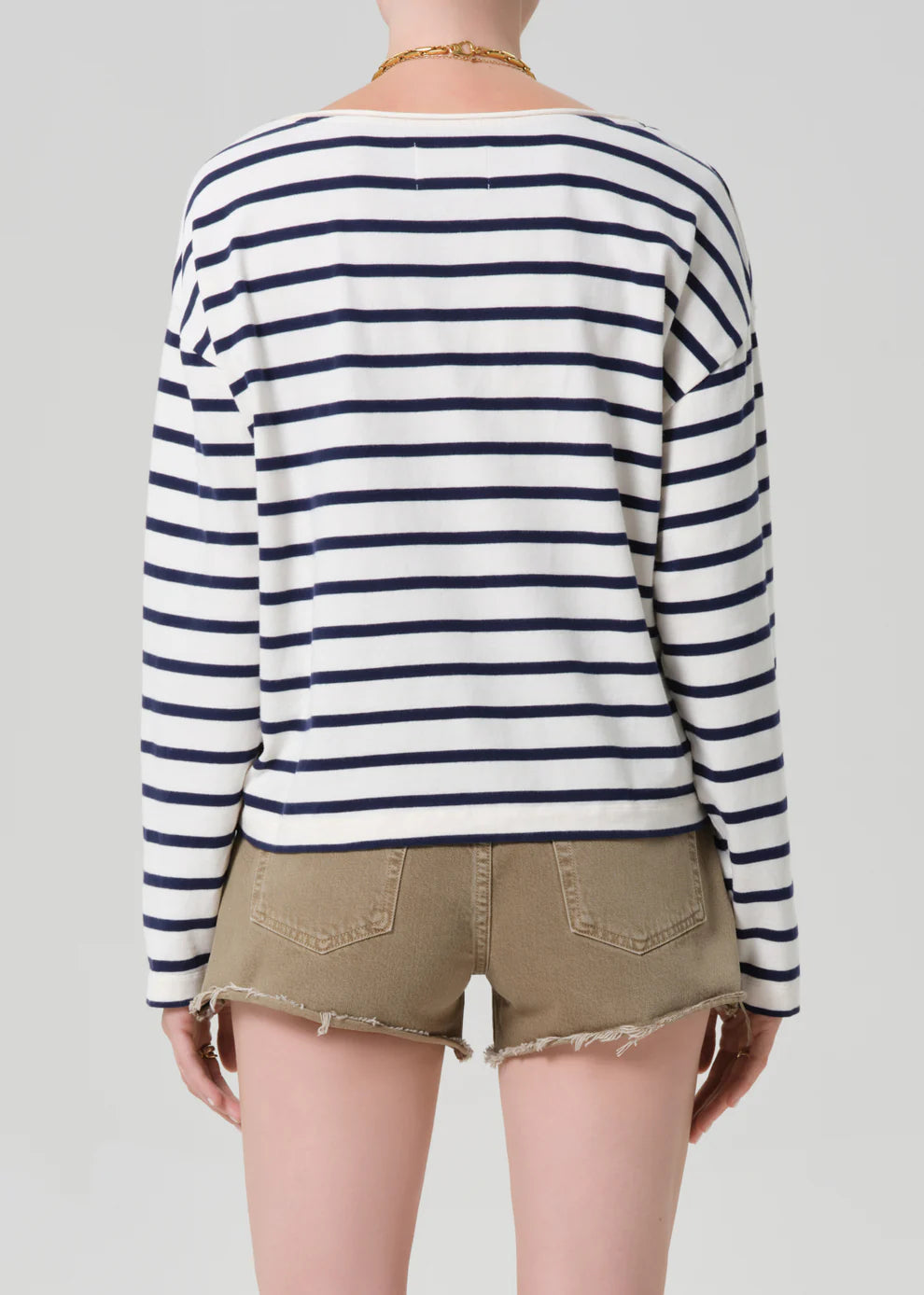 Person wearing a striped long-sleeve shirt and shorts on a plain background