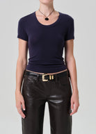 Person wearing a navy blue top and black leather pants on a gray background