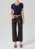 Person wearing a navy blue top and black leather pants on a white background