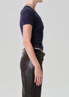 Person wearing a dark blue t-shirt and black leather pants on a light gray background
