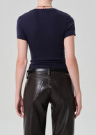 Person wearing a navy blue t-shirt and black leather pants on a light gray background
