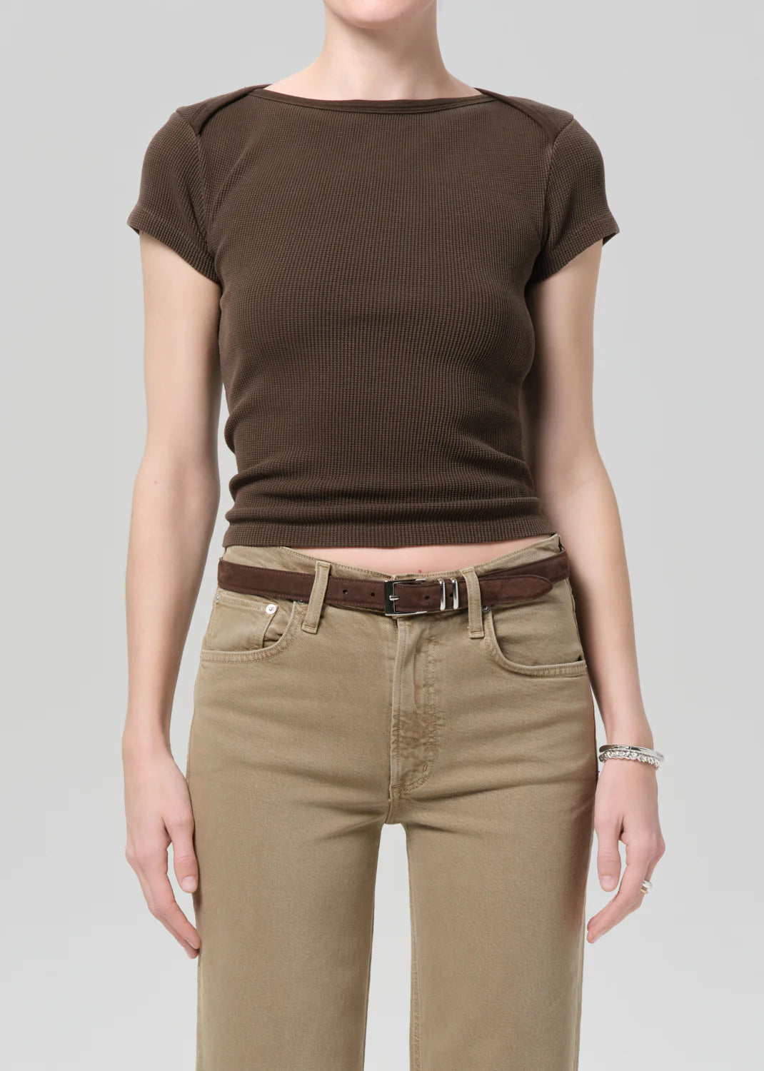 Person wearing a brown top and beige pants on a plain background