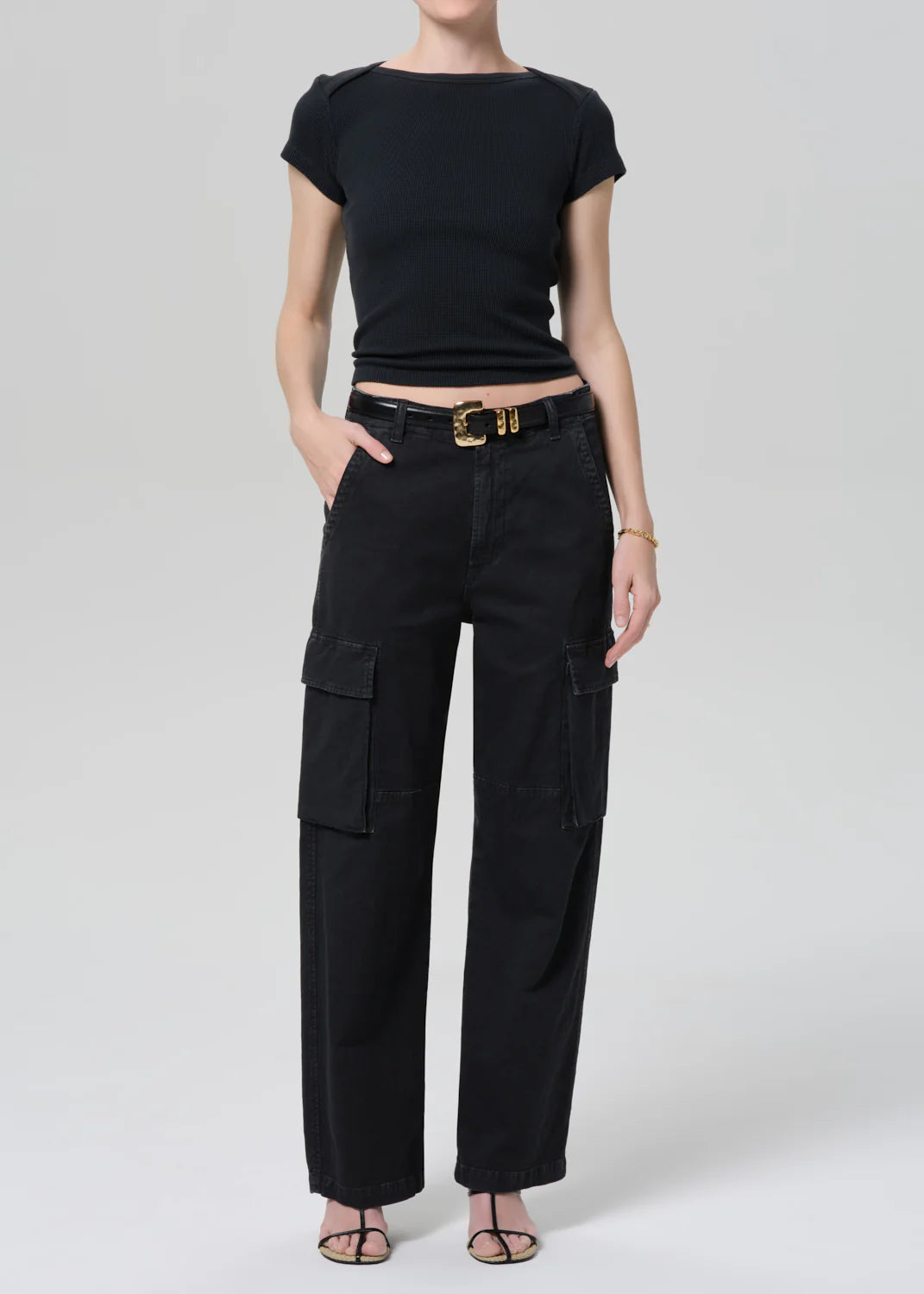 Person wearing a black outfit with a belt on a white background