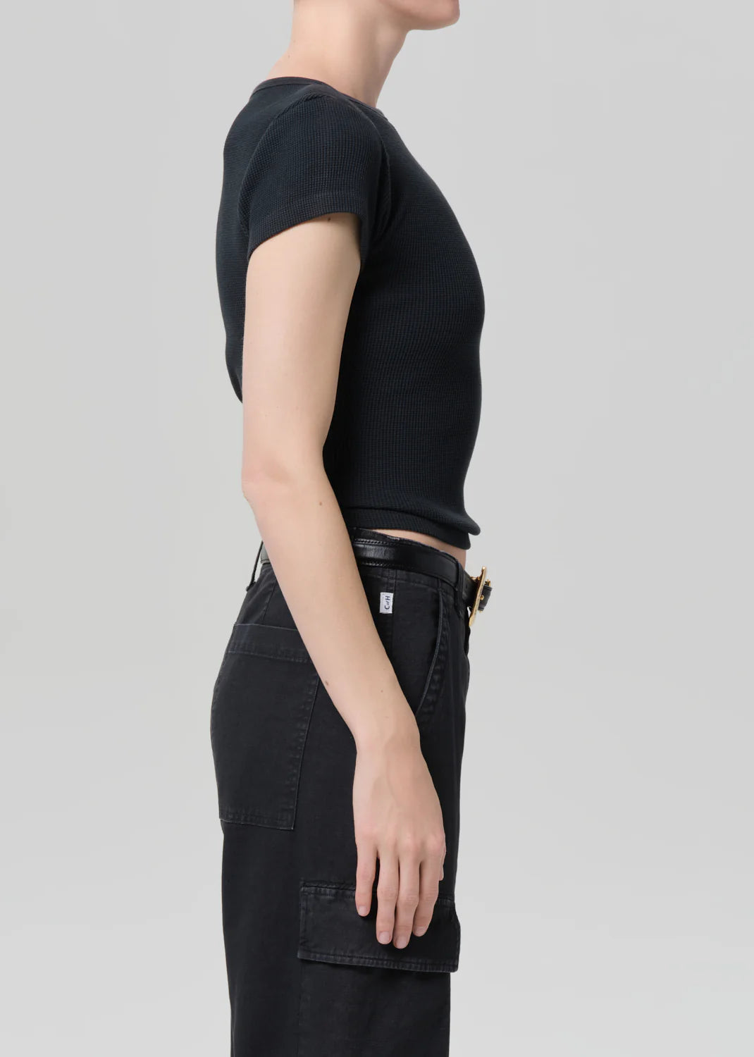 Person wearing a black t-shirt and black pants on a light gray background