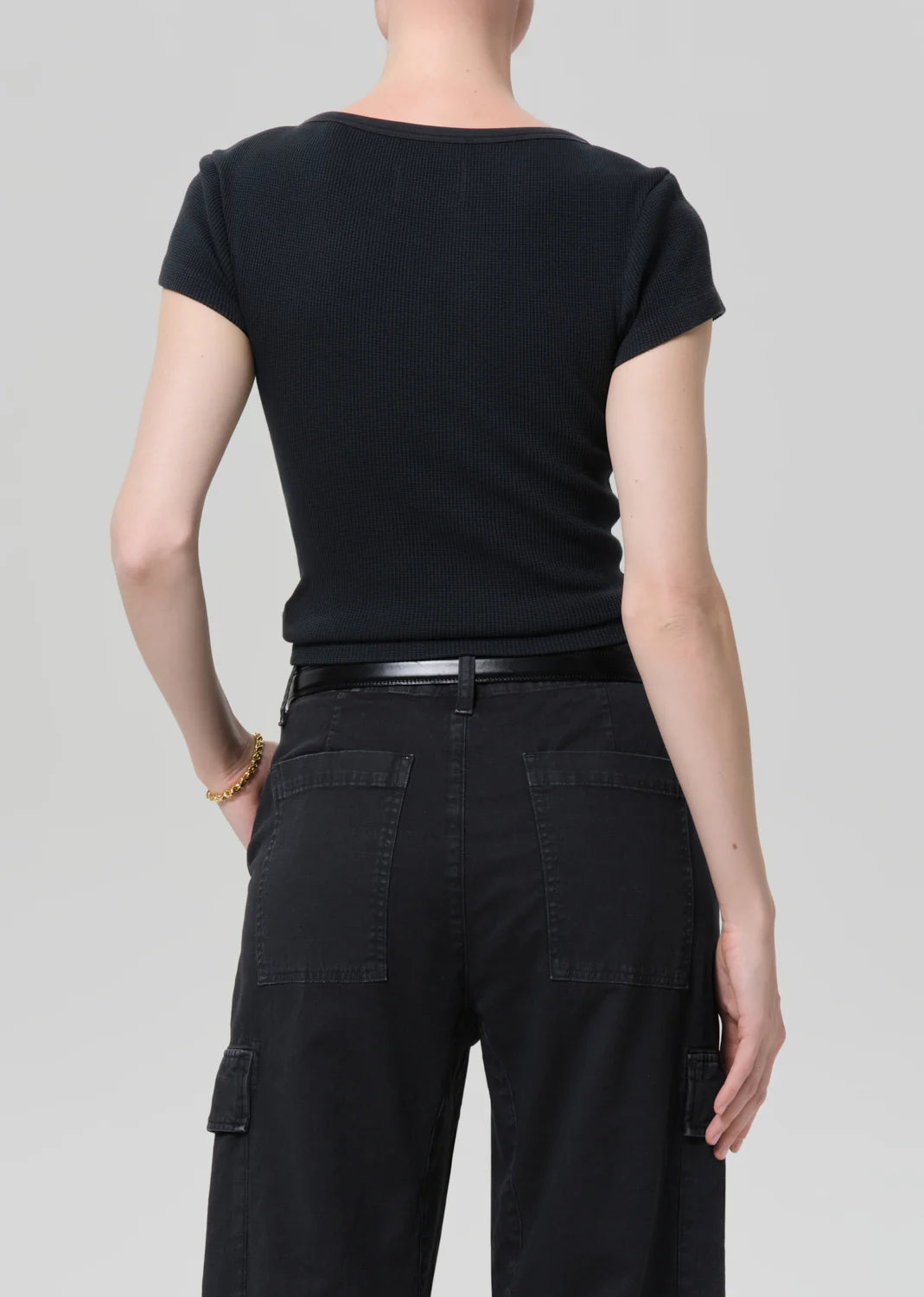 Person wearing a black t-shirt and black pants on a light gray background