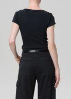 Person wearing a black t-shirt and black pants on a light gray background