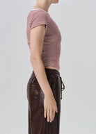 Side profile of a model wearing a short-sleeve striped crop top in red and white, paired with dark brown pants, against a light gray studio background.
