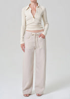 Person wearing a cream-colored outfit with a cardigan and wide-leg pants on a white background