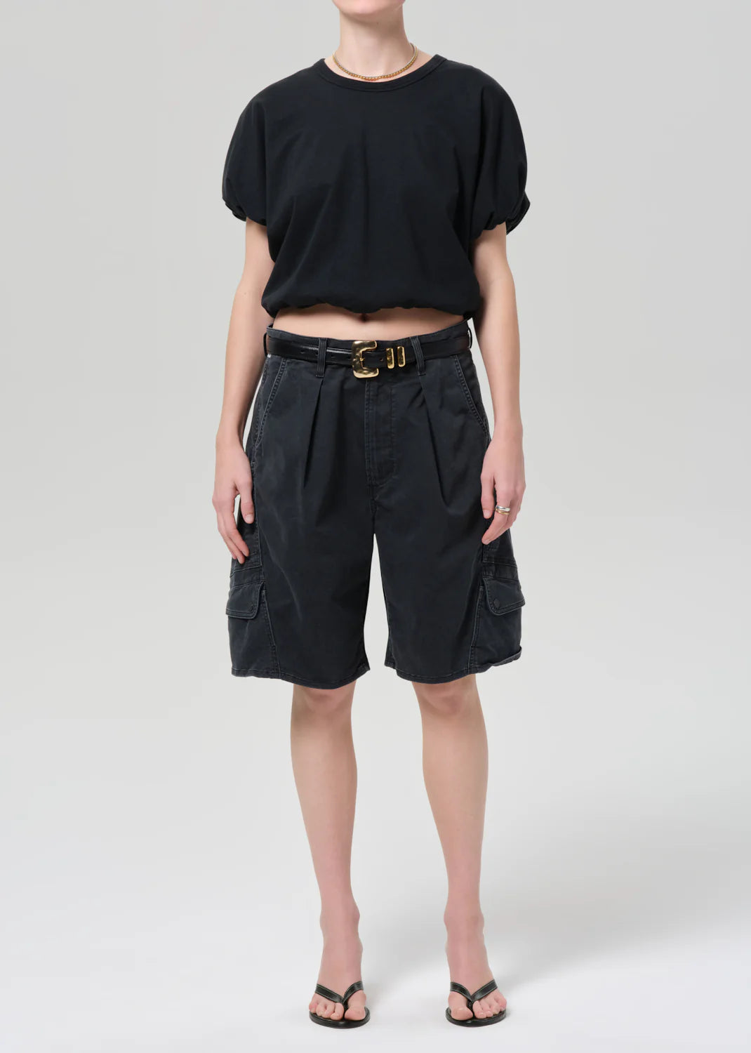 Person wearing a black top and dark gray shorts on a white background