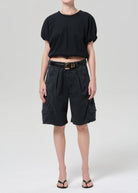 Person wearing a black top and dark gray shorts on a white background