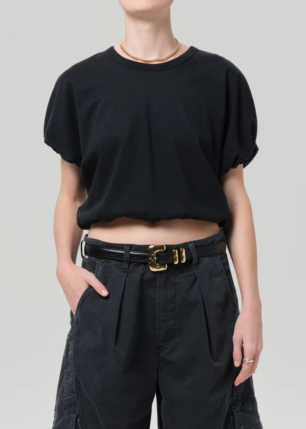 Front side view of a model wearing a black top and dark gray shorts on a white background