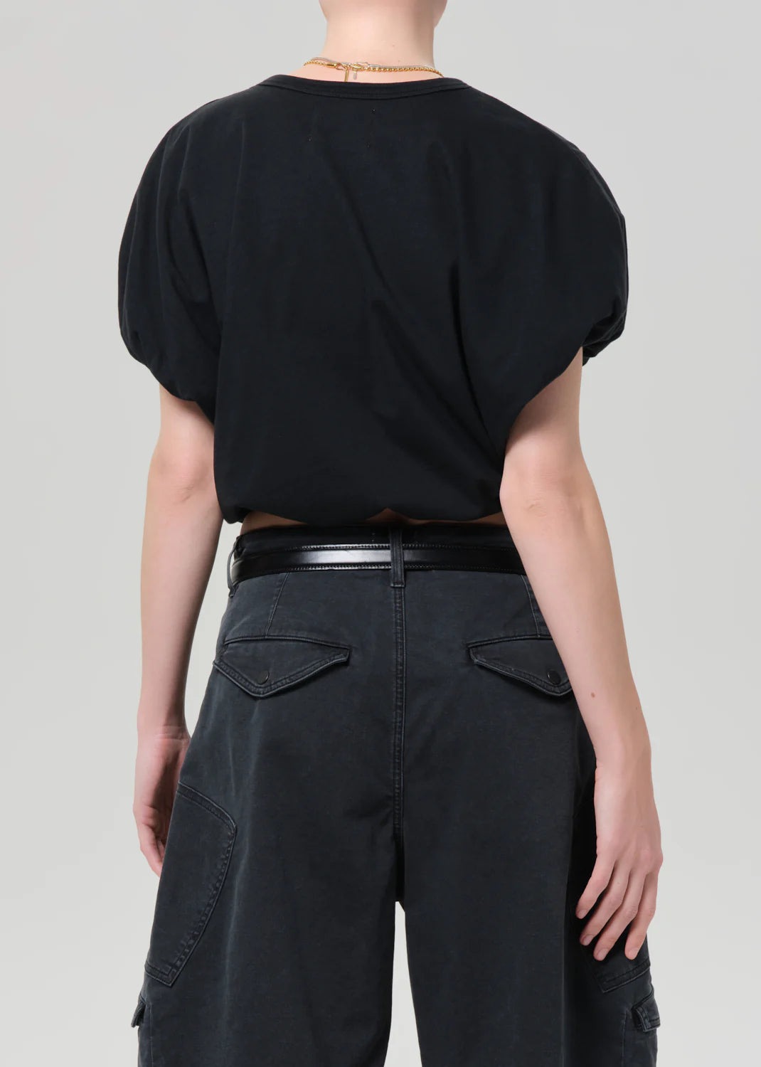 Back side view of a model wearing a black top and dark gray shorts on a white background
