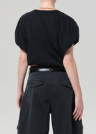Back side view of a model wearing a black top and dark gray shorts on a white background